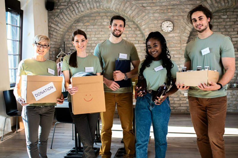 Portrait of volunteers with working in community charity donation center.